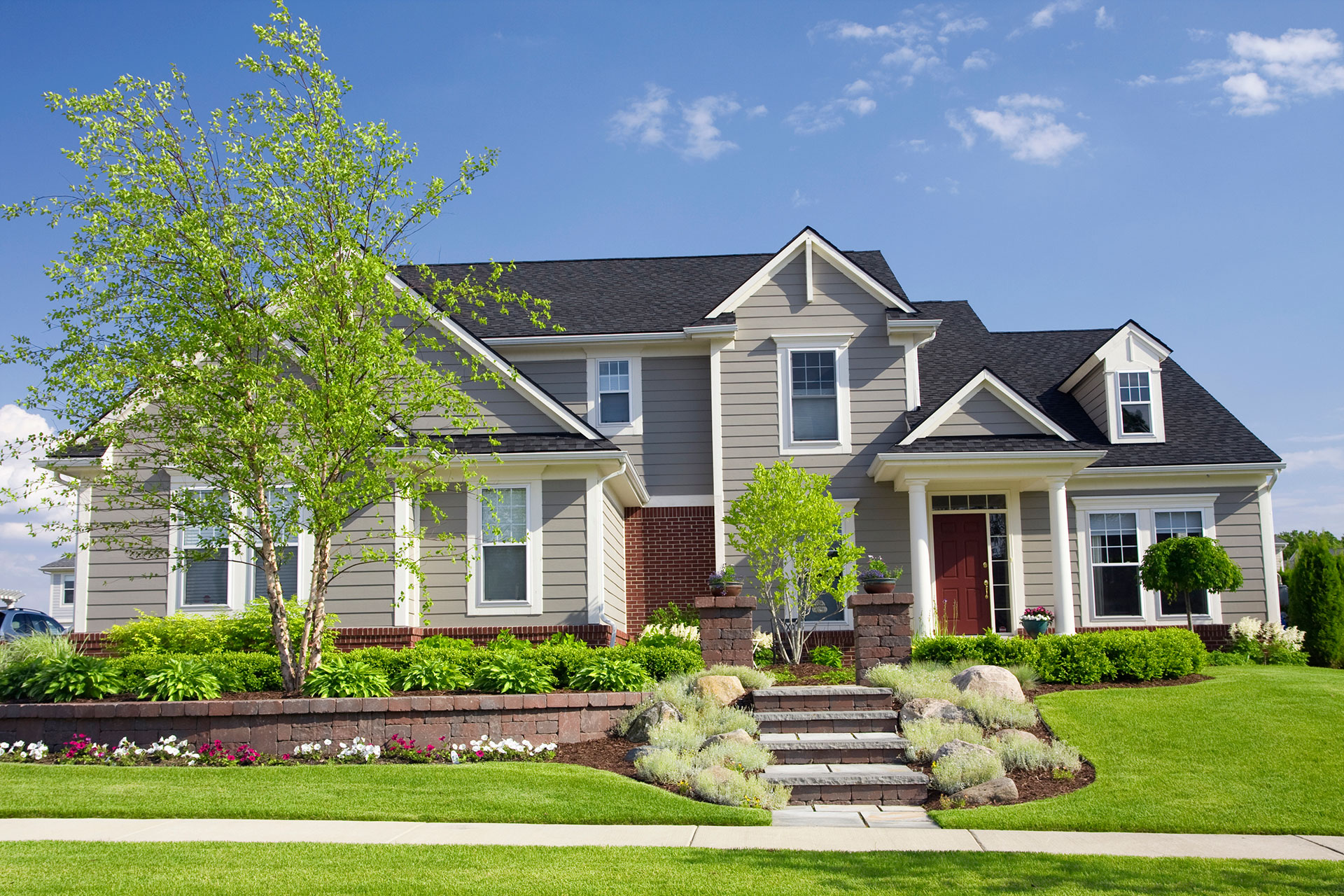 large two story family home with steps up walkway and tree in front